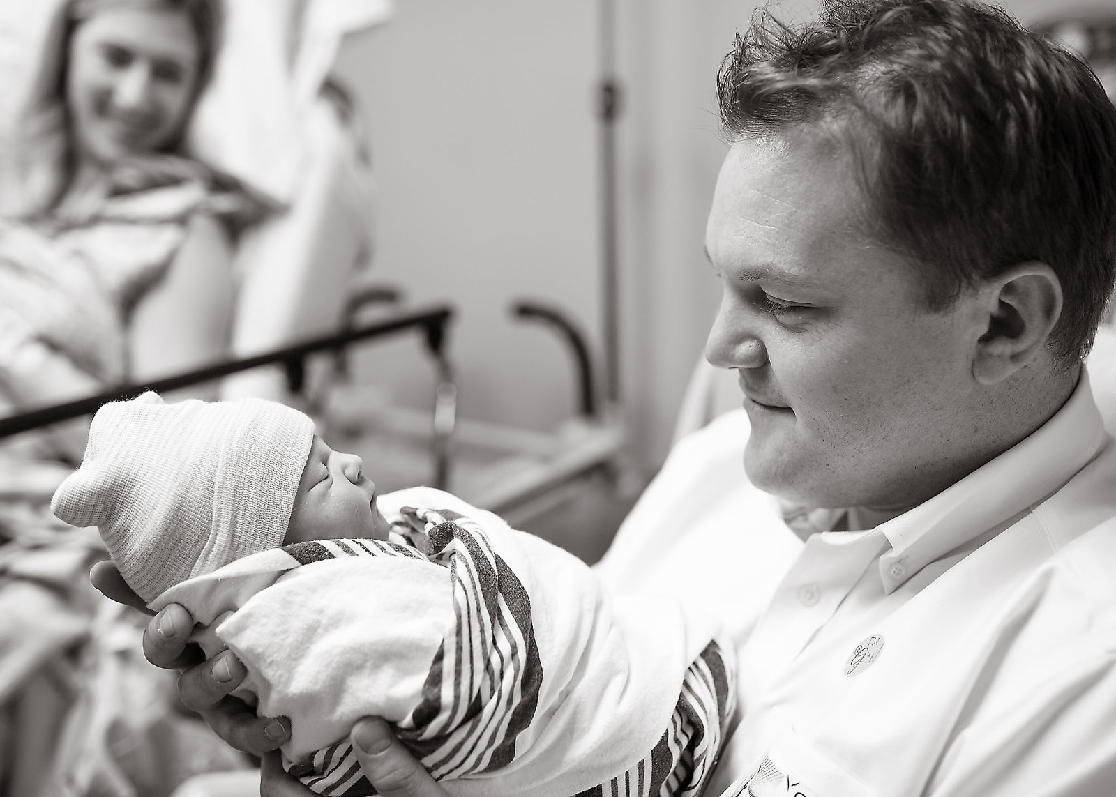 Daddy hold newborn baby while mommy watches