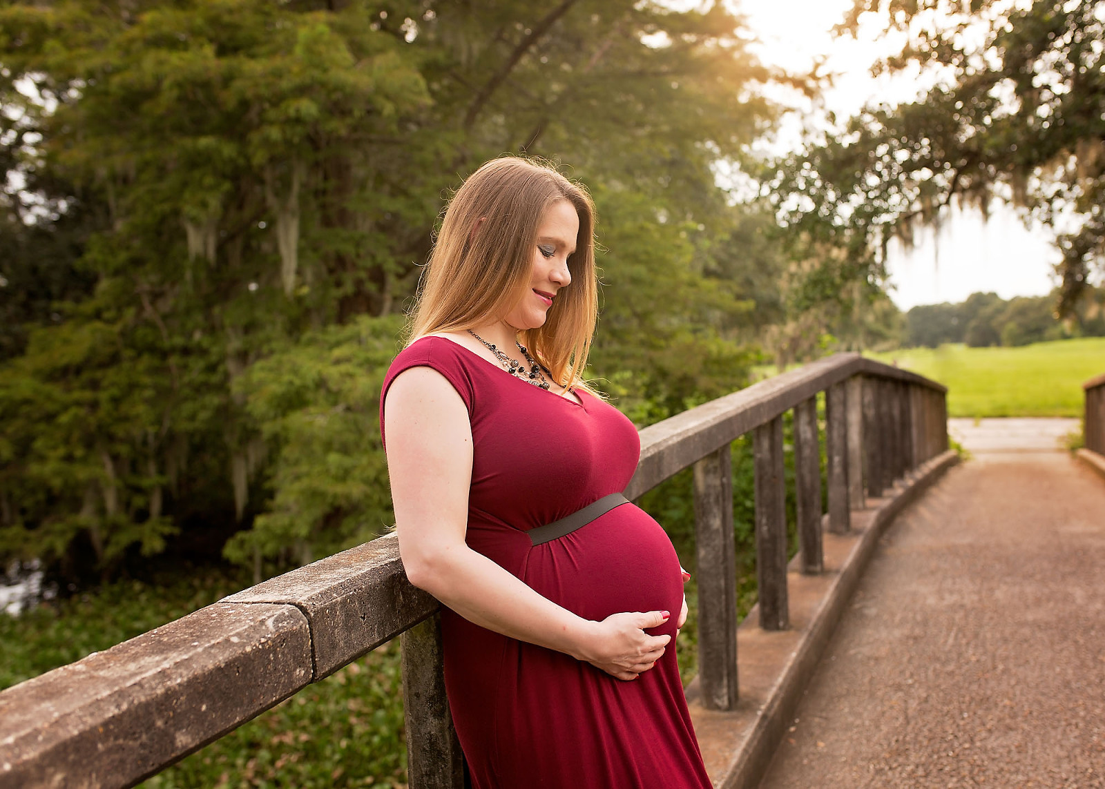 mommy to be red dress holding belly bridge