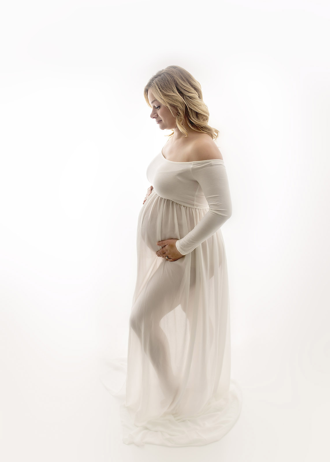 standing mother to be in white sheer dress backlit portrait