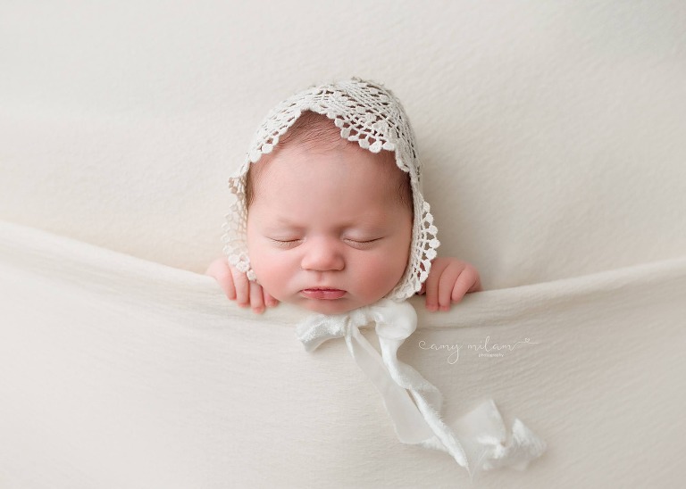 tucked in newborn girl with lace bonnet